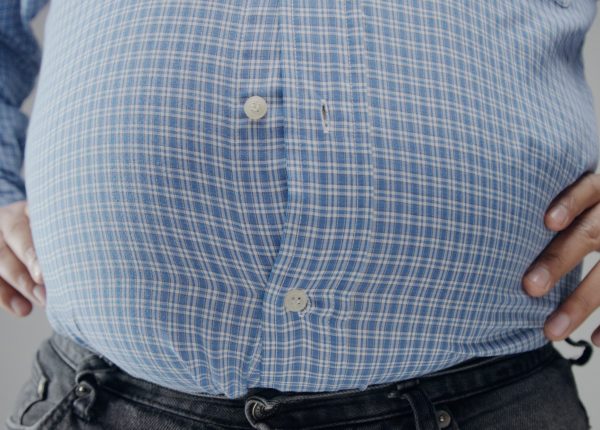 Overweight man in shrt is small to him with huge belly and open buttons