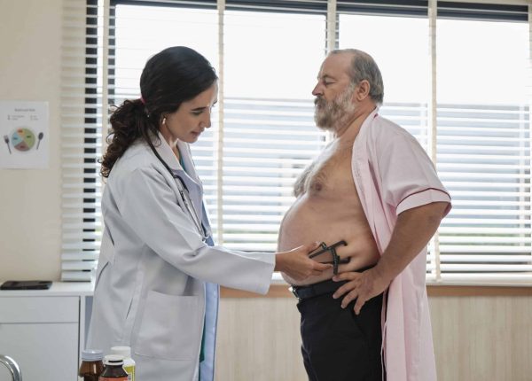 Female doctor and professional nutritionist in uniform with caliper examine White patients by stands and fat measure, checkups for healthy diet at clinic hospital, and appointments visit.